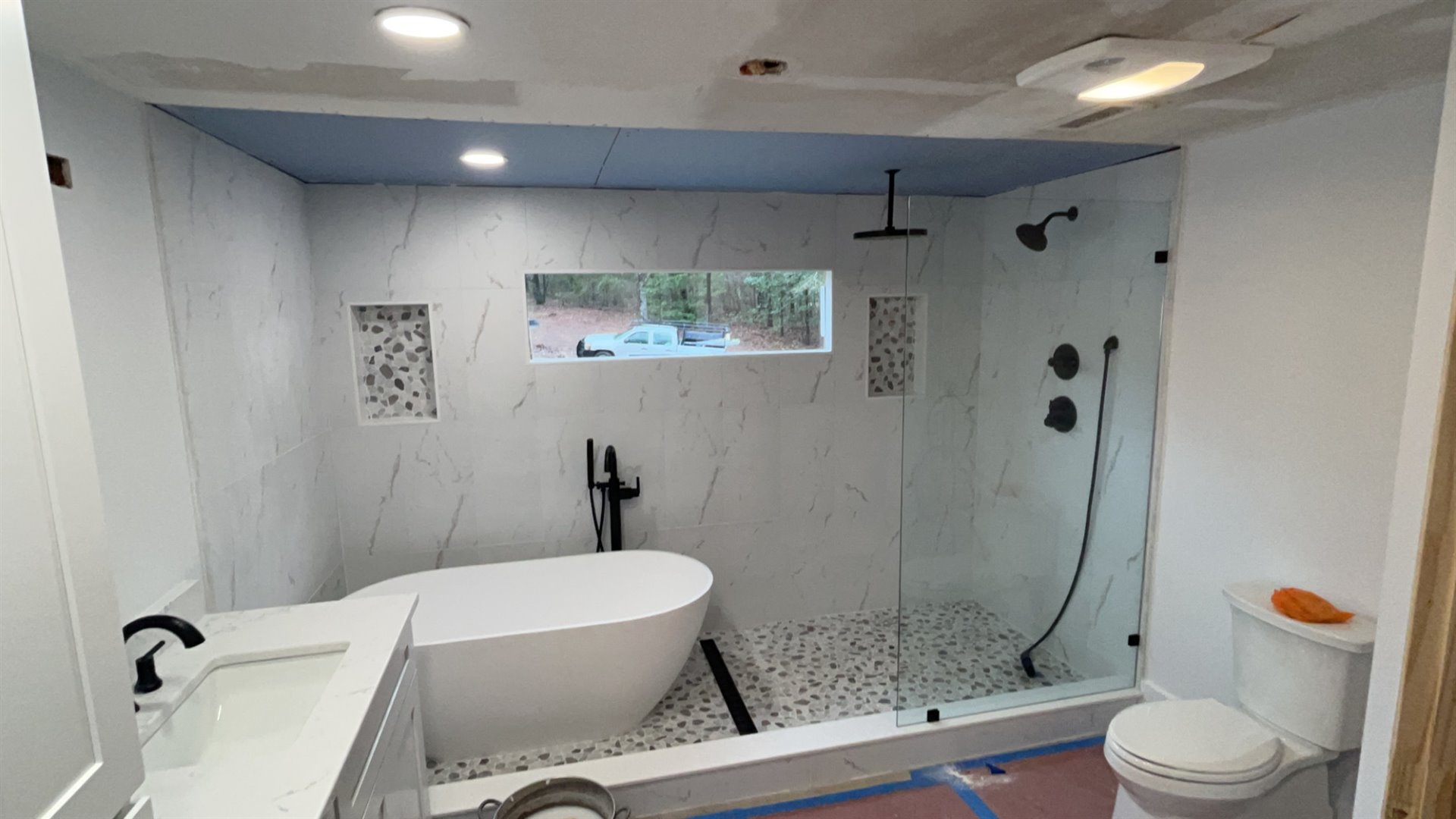 Bright remodeled bathroom with a freestanding tub and glass-enclosed tile shower