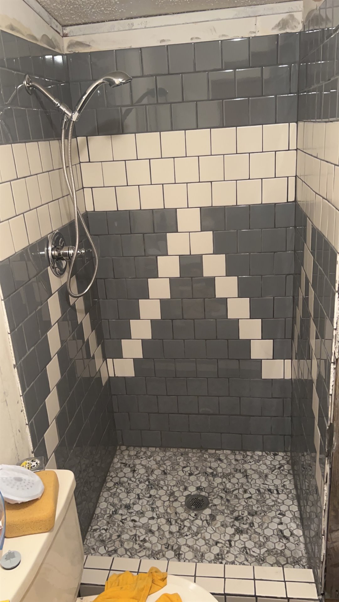 Gray and white tile shower with a hexagonal mosaic floor
