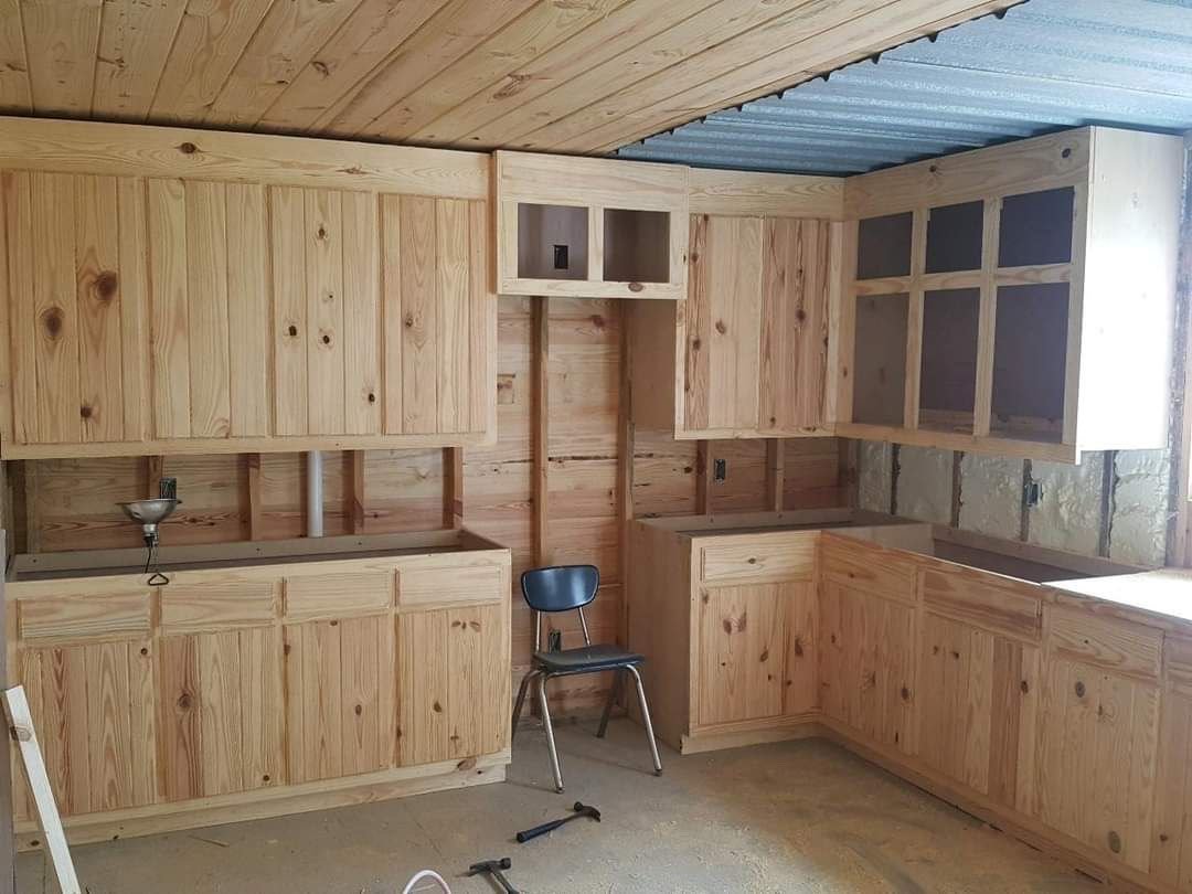 Custom wood cabinets fitted along the walls of a kitchen in progress