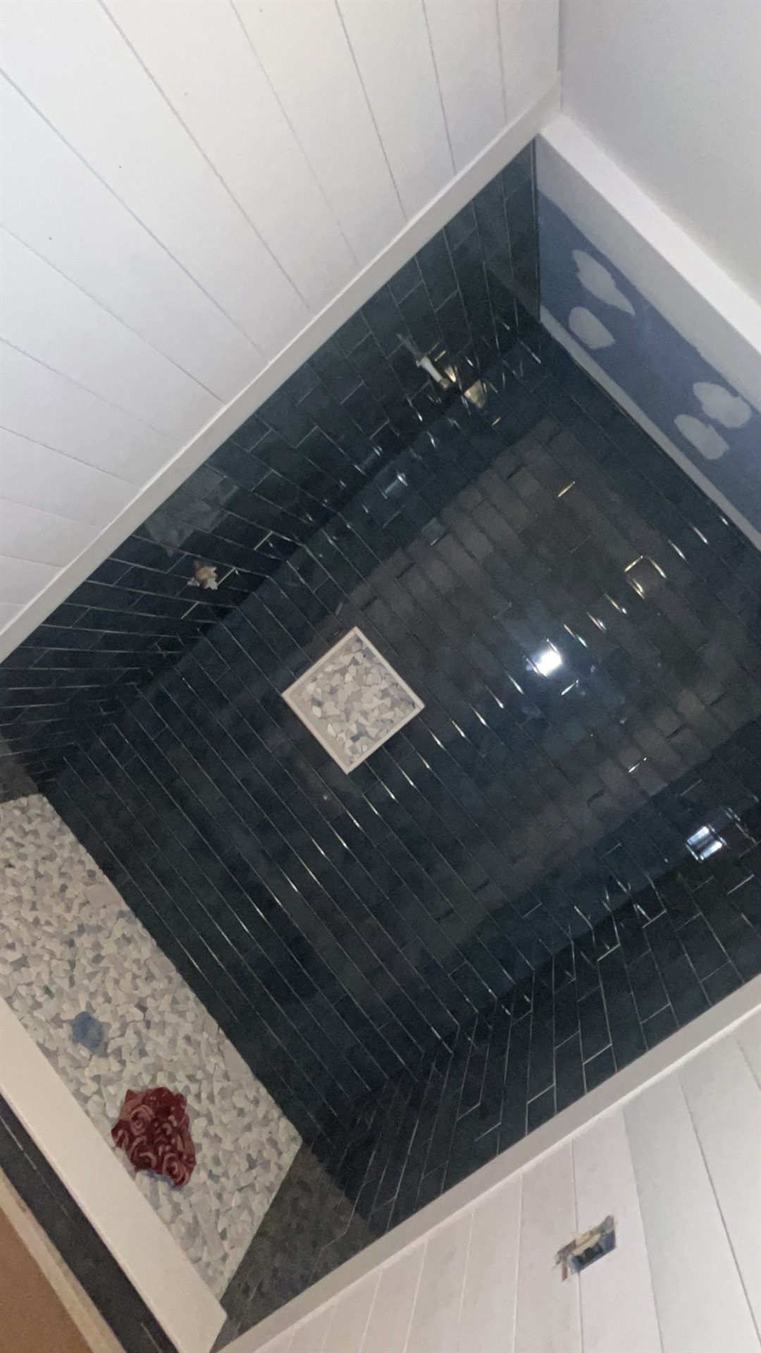 Dark tile shower with a light mosaic floor and white trim