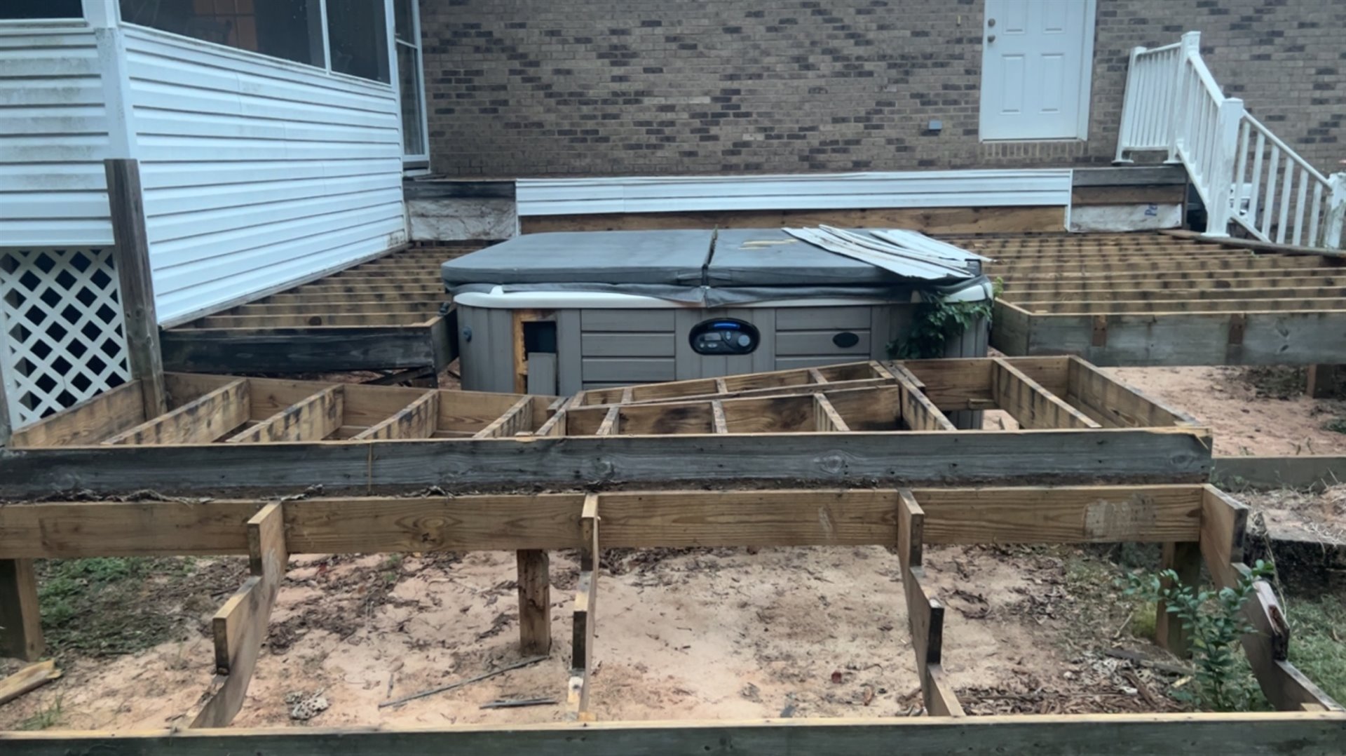 New deck framing laid out beside a home and hot tub