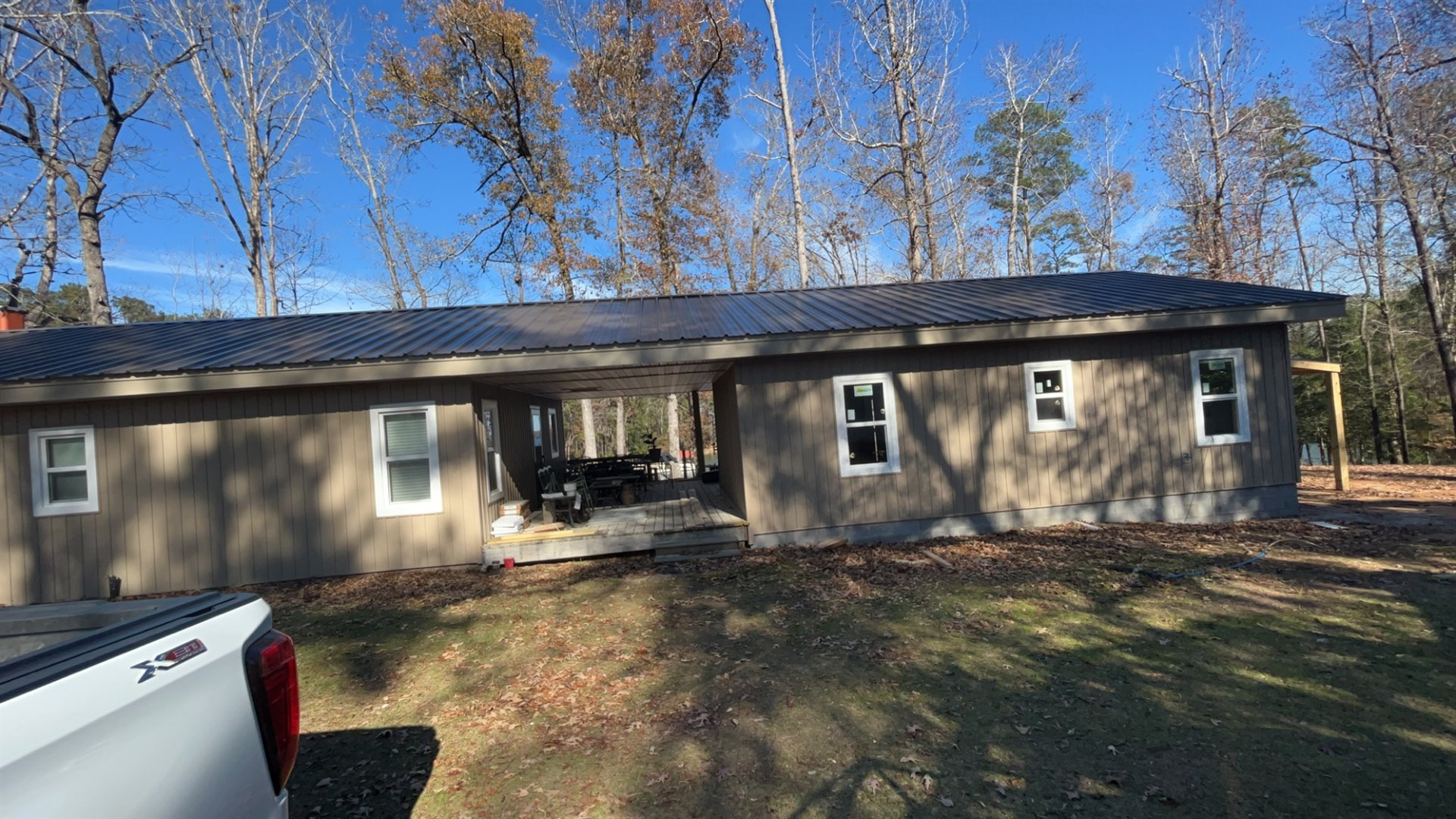 Completed home with a covered central porch, metal roof, and wooded setting