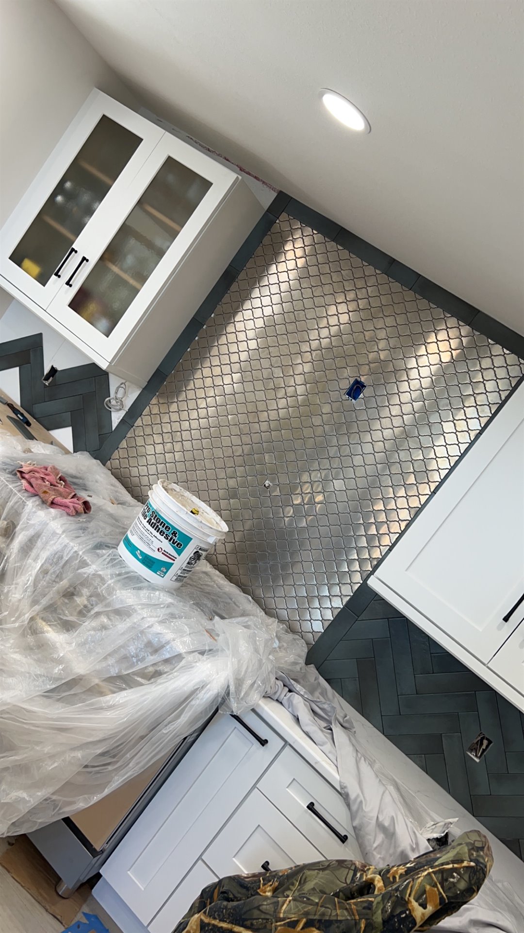 Decorative patterned tile installed between white kitchen cabinets